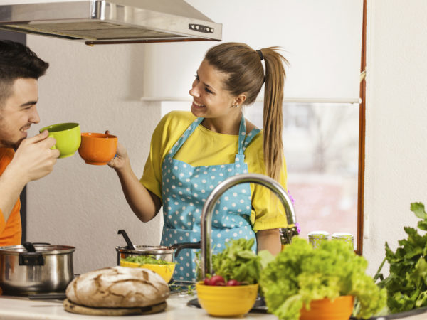 Couple toasting with coffee in kitchen while cooking together