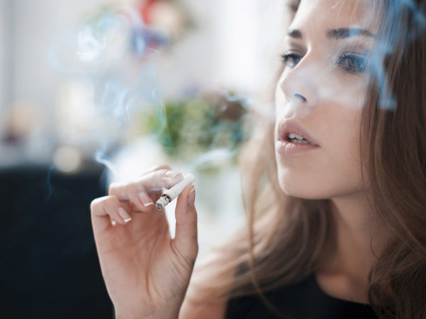 The thoughtful woman smokes a cigarette.