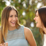 Happy women talking and laughing in a park with a green background