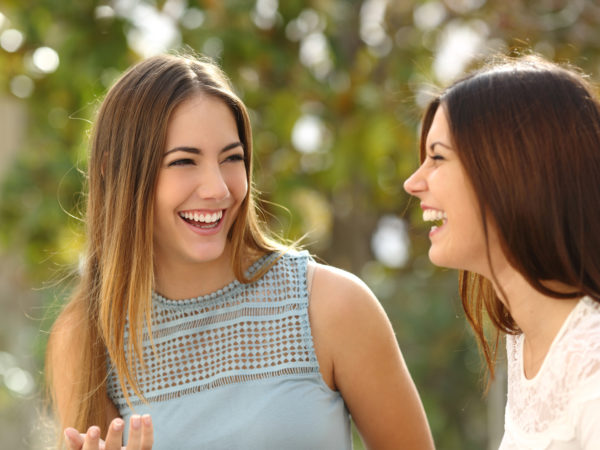 Happy women talking and laughing in a park with a green background