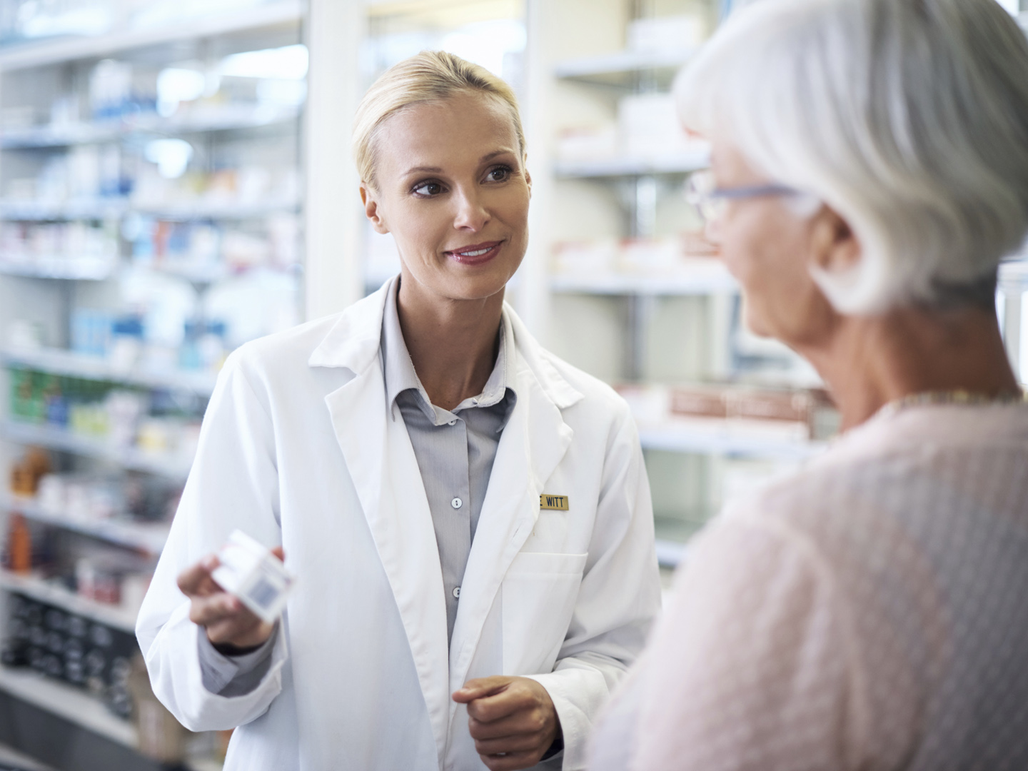 Shot of a young pharmacist helping an elderly customer