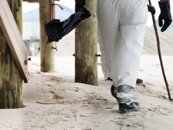 The legs of a person looking for tar balls while cleaning up the beach after an oil spill disaster.