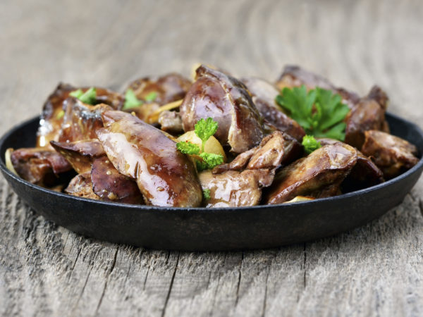 Chicken liver in frying pan on wooden table