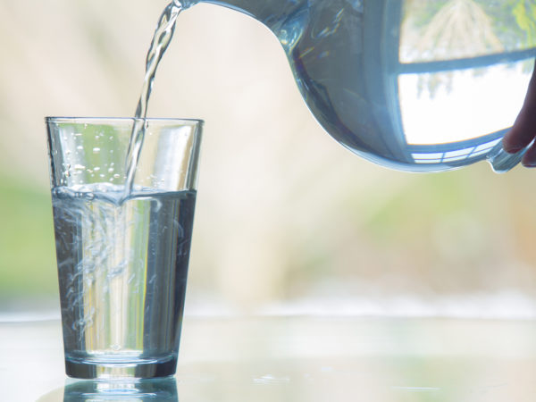 Water being poured from a glass pitcher into a glass.