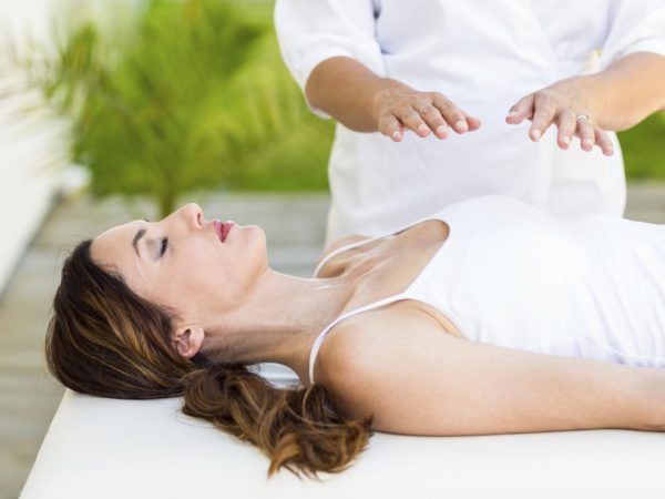 Calm woman receiving reiki treatment in the health spa