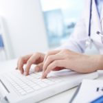 Close-up of hands of a nurse typing on laptop