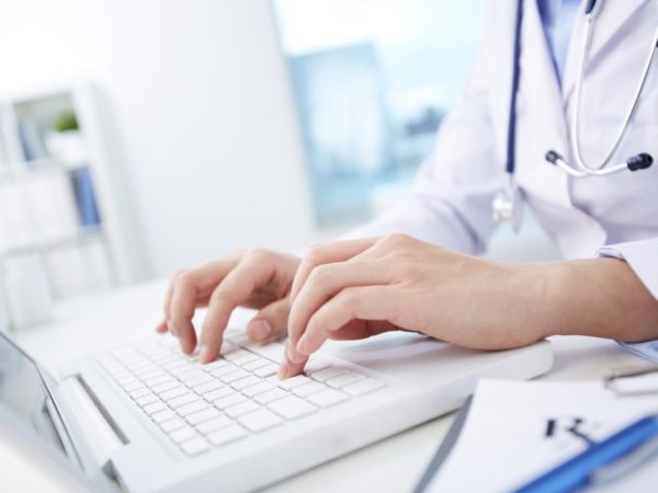 Close-up of hands of a nurse typing on laptop