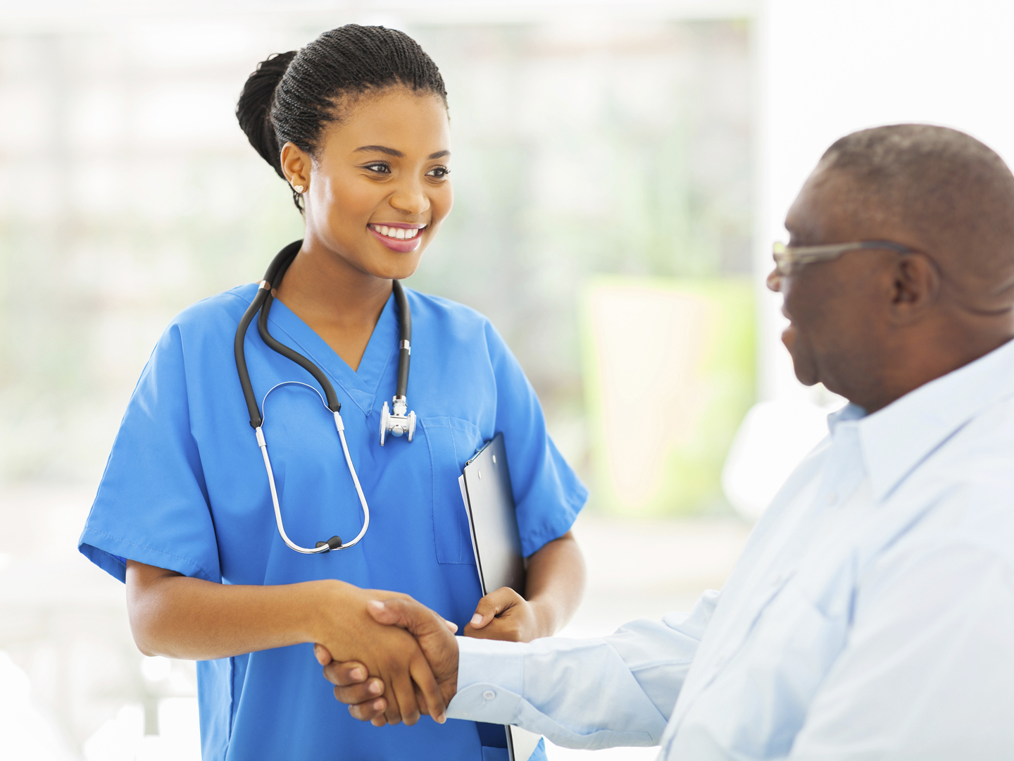 friendly african american medical nurse handshaking with senior patient