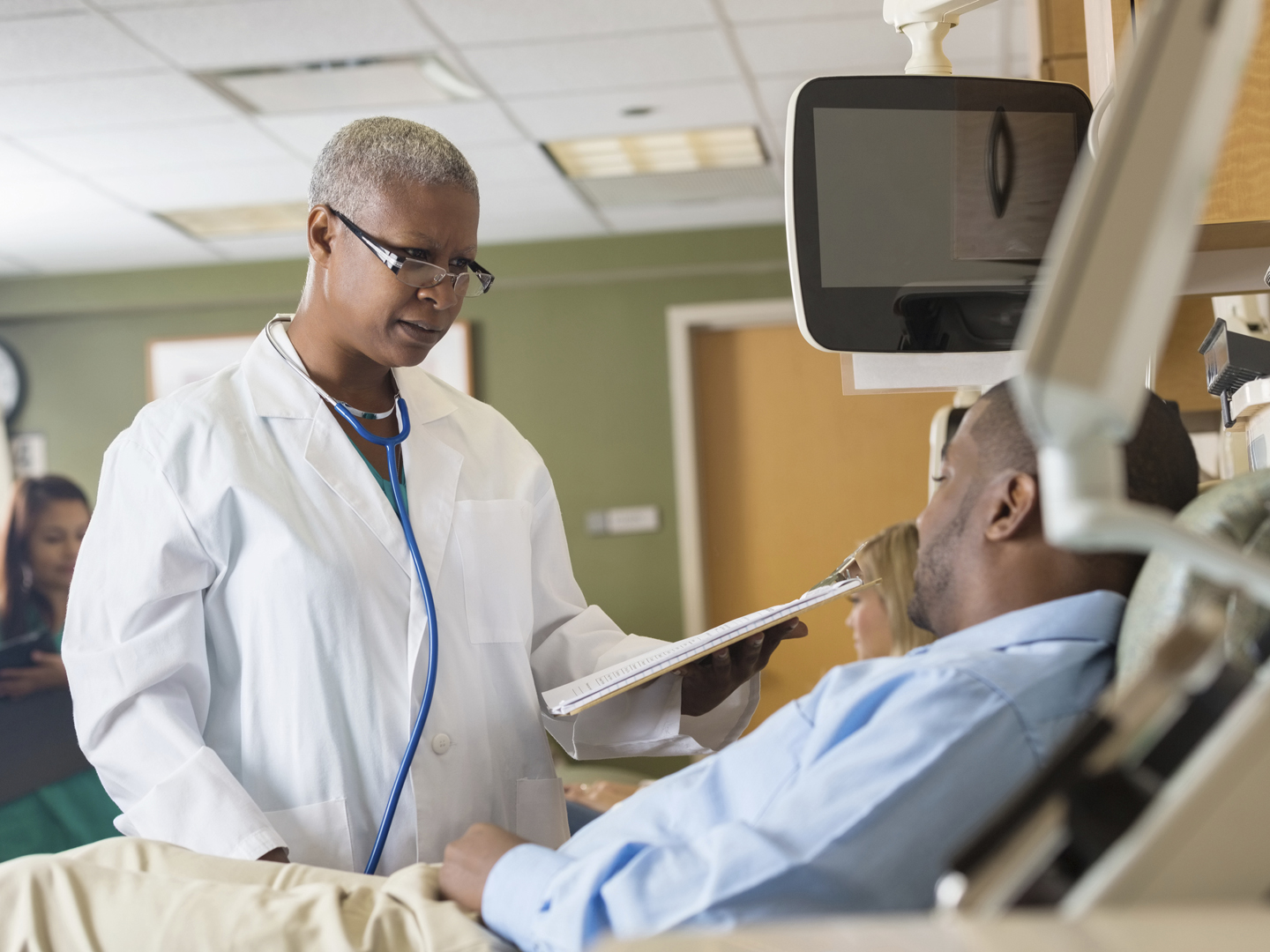 Female African American doctor explaining chart to patient in hospital