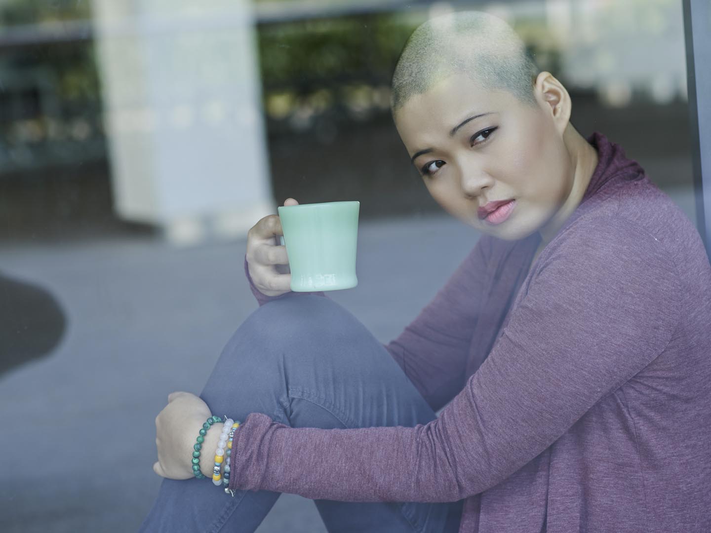 Portrait of sad Asian with a cup of tea sitting at window