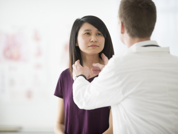 A woman is at a doctors appointment to get her soar throat checked out. The doctor is asking her medical questions.