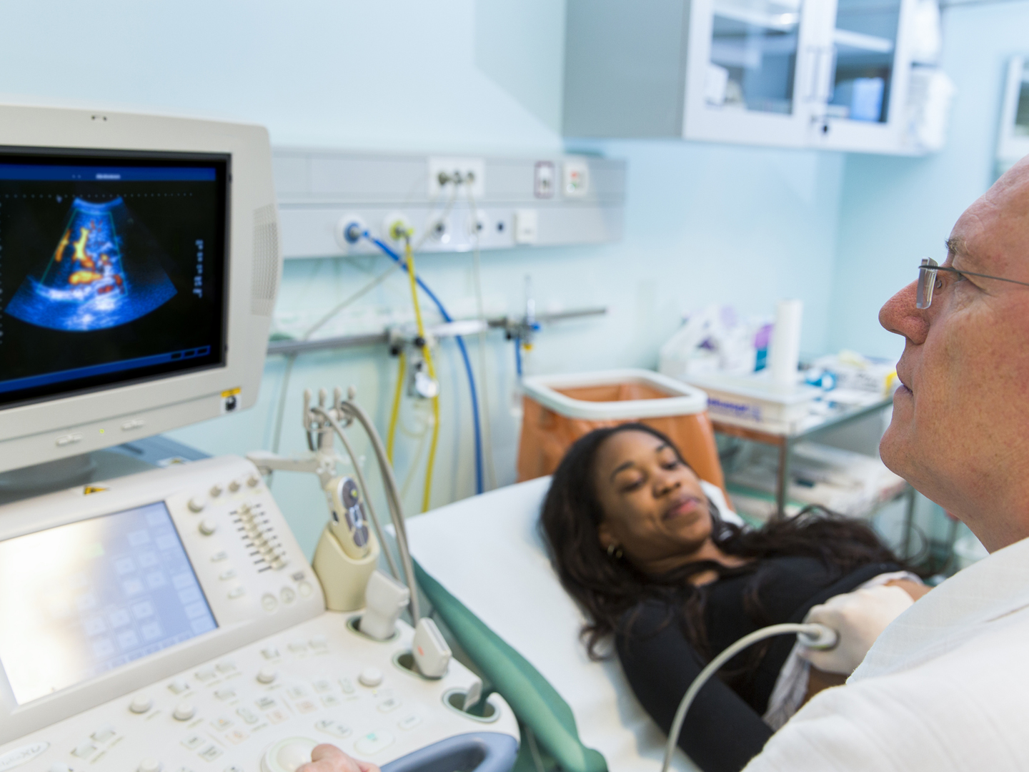 Doctor is giving black  young woman an ultra sound...young women doctor assisting