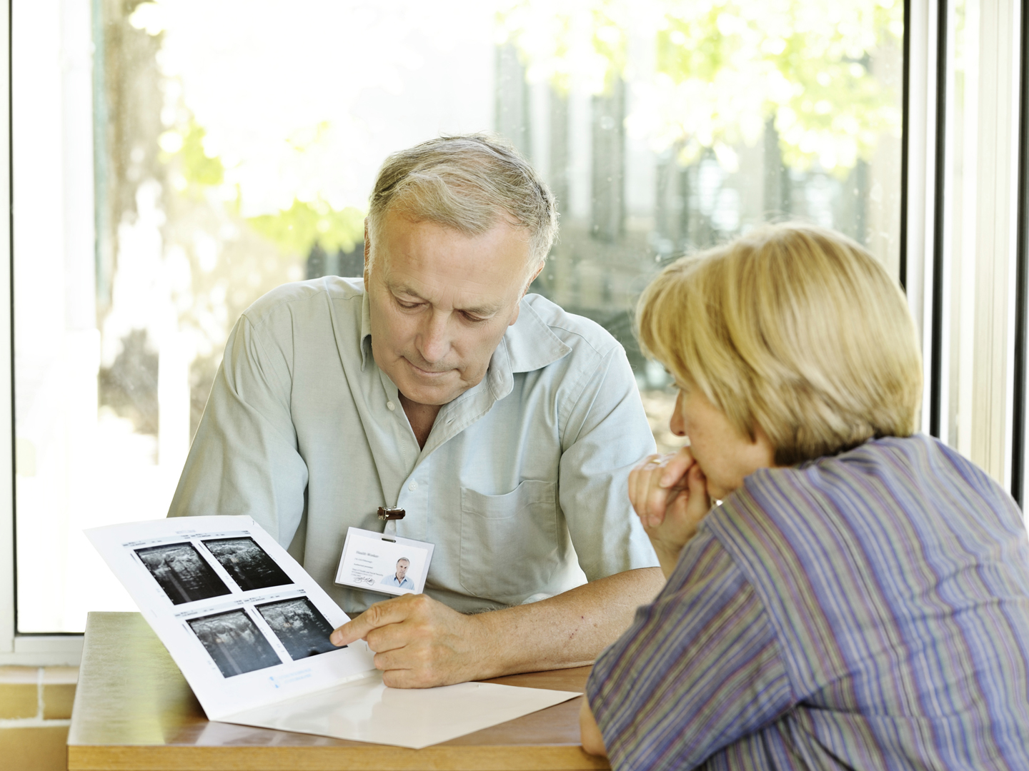 ** ID badge made entirely by photographer ** Specialist doctor explains scans to woman. The scans are blurred for varied use but are actually scans of the uterus for gynaecological tests.