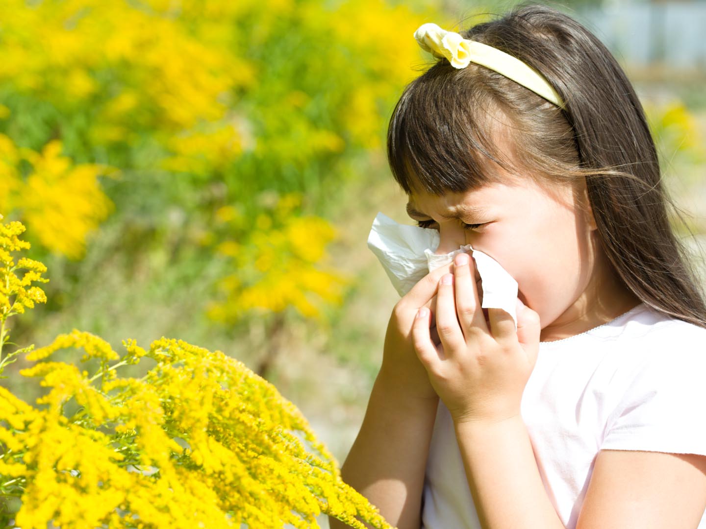 Girl is blowing her nose, allergic to bloom flowers