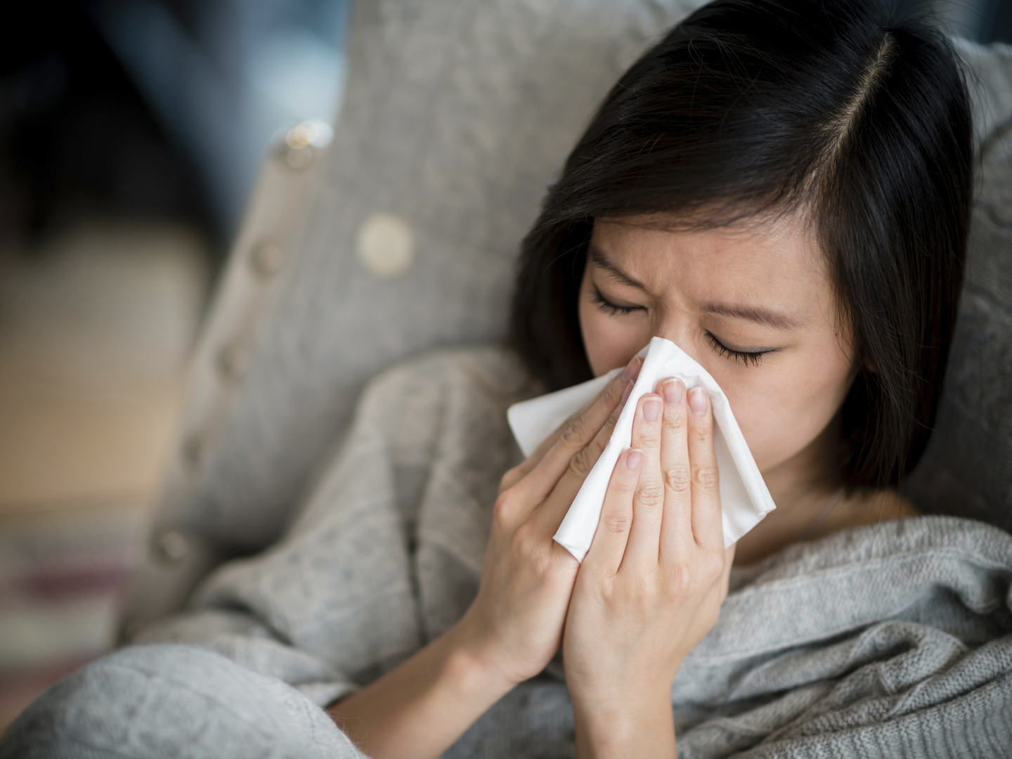 Ill woman with the flu blowing her nose