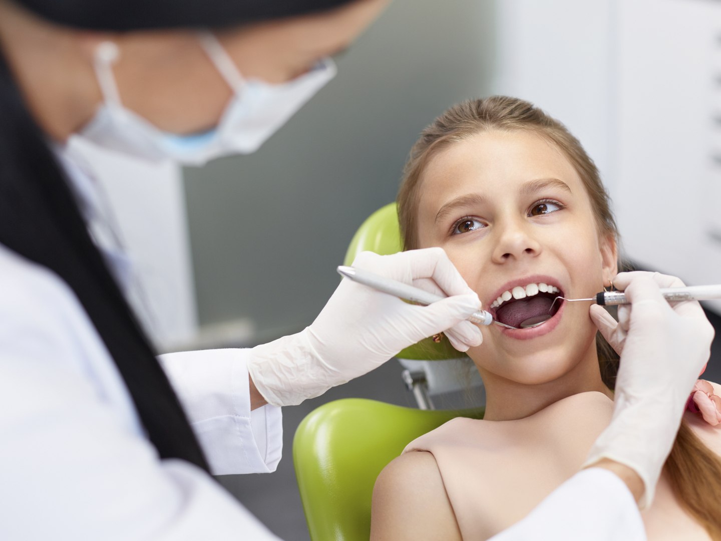 Teeth checkup at dentist&#039;s office. Dentist examining girls teeth in the dentists chair