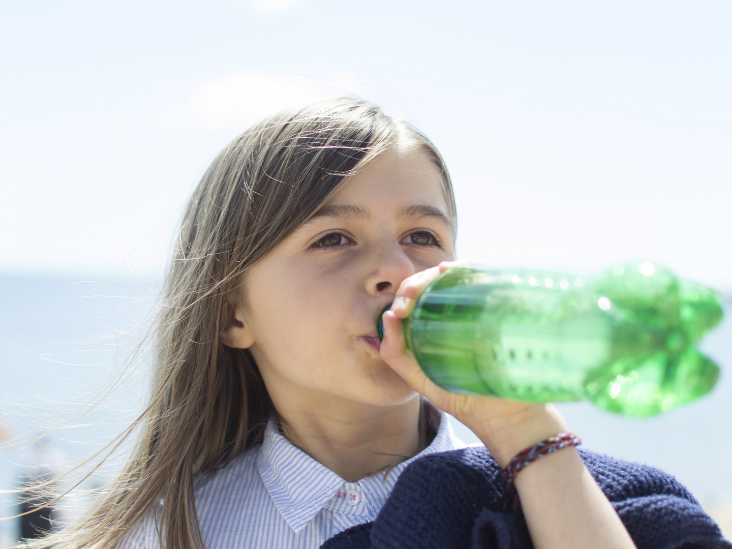 A child drinking a soft drink/pop/soda from a plastic bottle