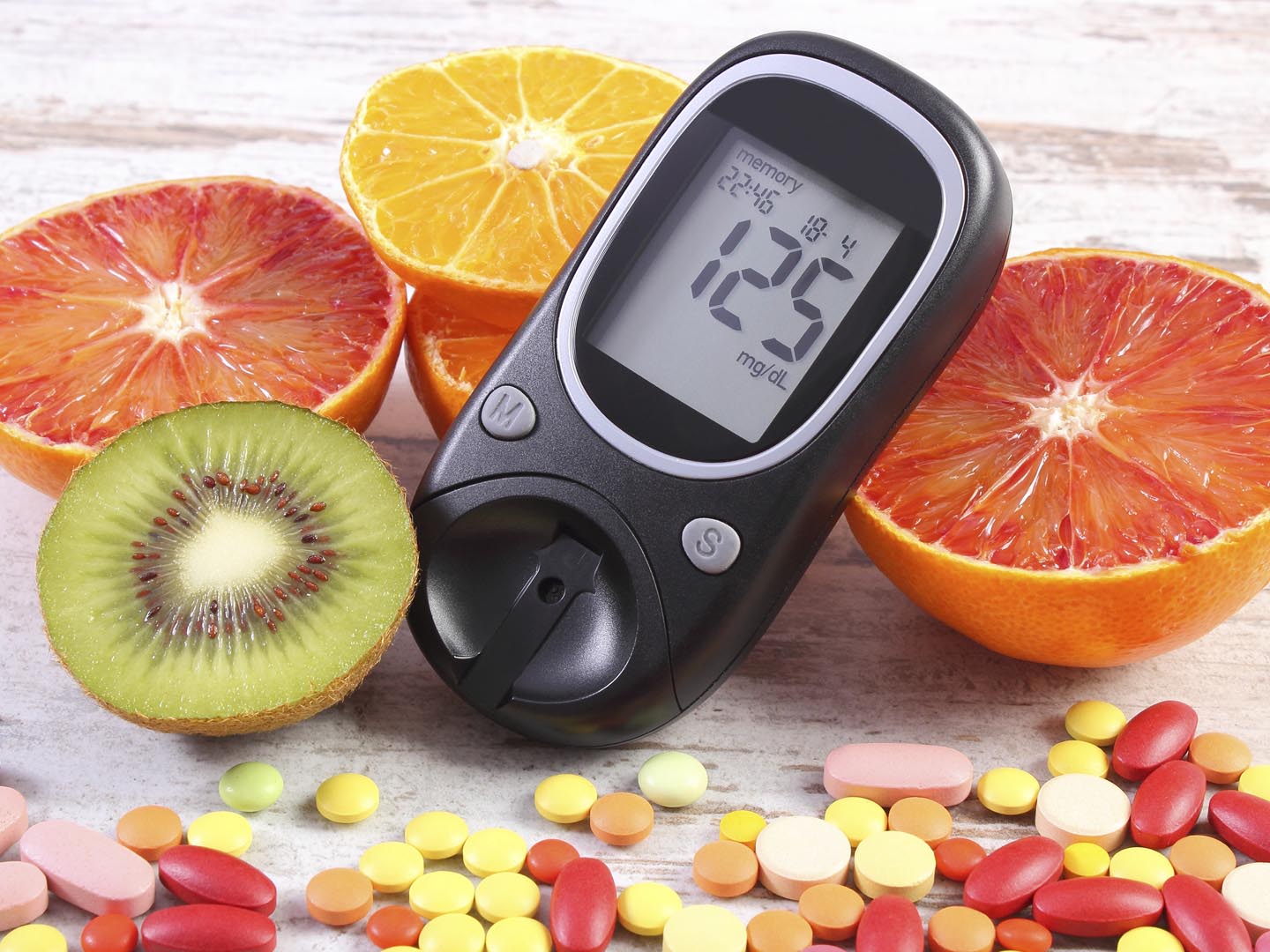 Glucose meter with result of measurement sugar level, fresh natural fruits and medical pills, tablets and supplements, concept of diabetes, healthy lifestyle and nutrition
