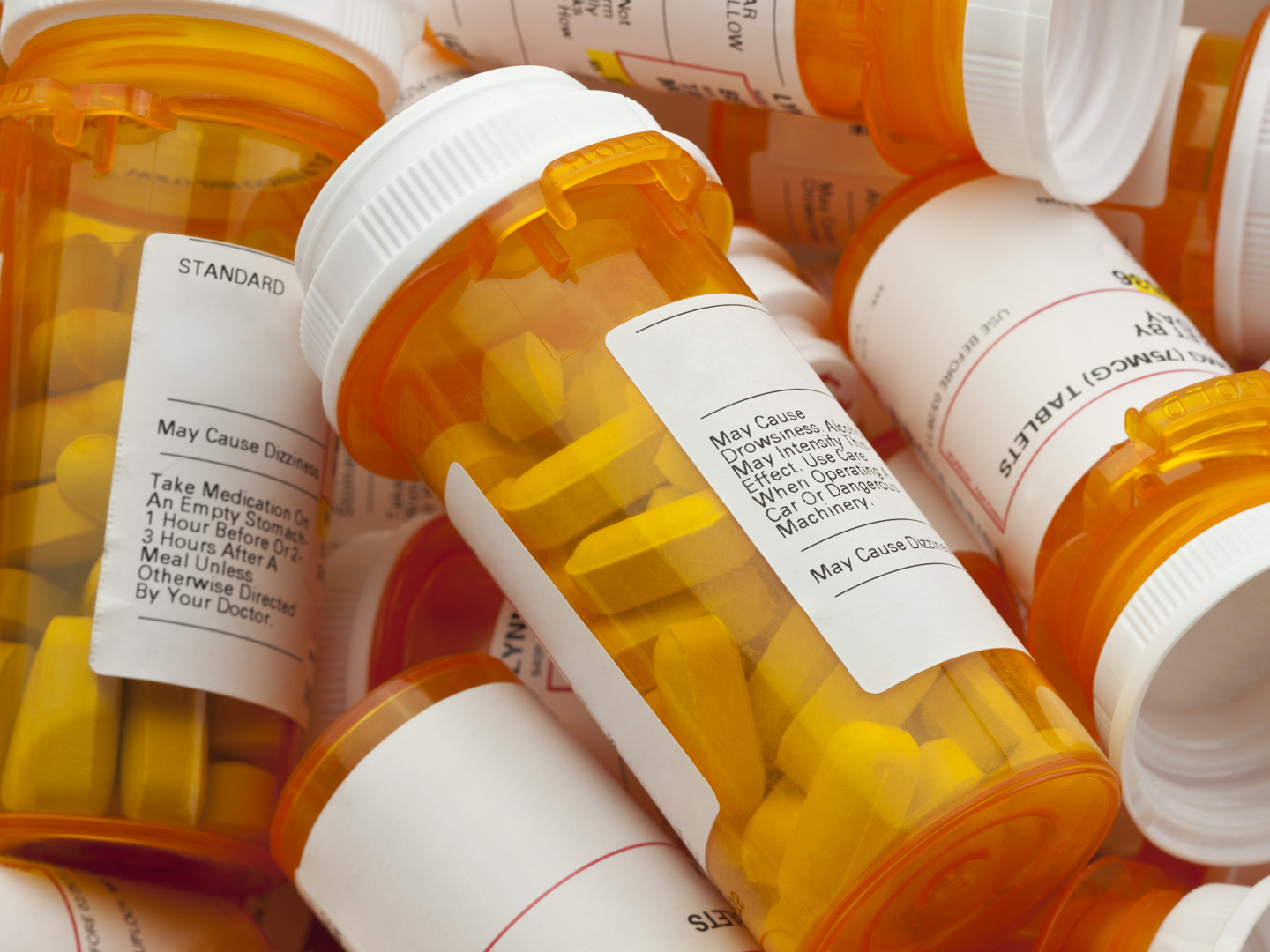 Bottles of prescription medicine in a pile. This collection of pill bottles is symbolic of the many medications senior adults and chronically ill people take.