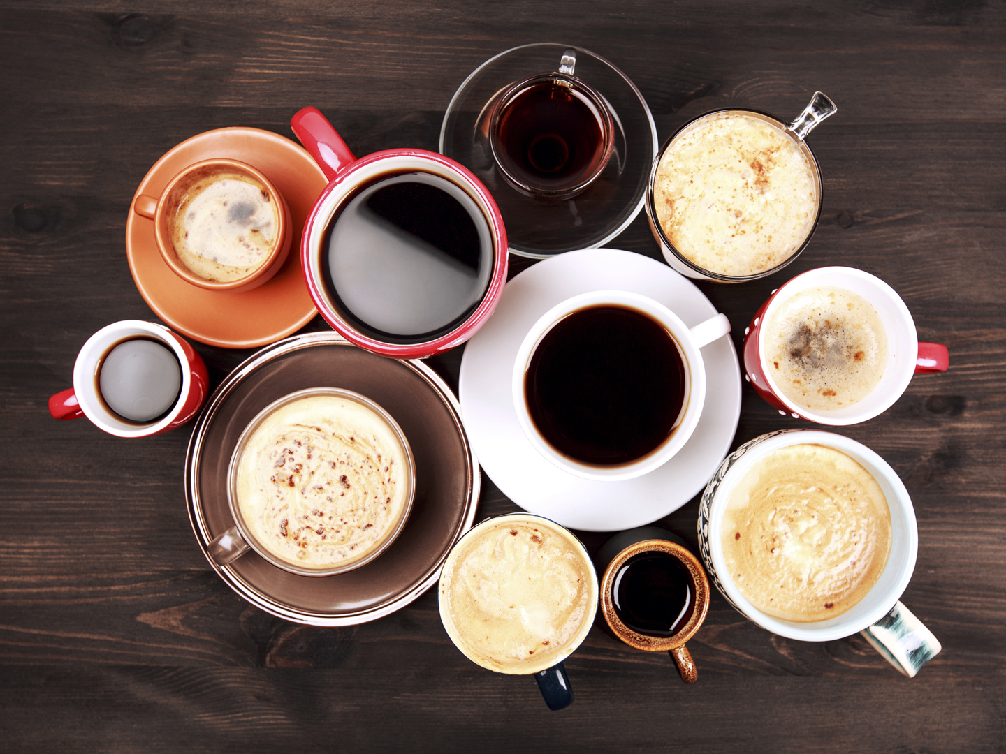 Many different cups of coffee on dark wooden table, top view.