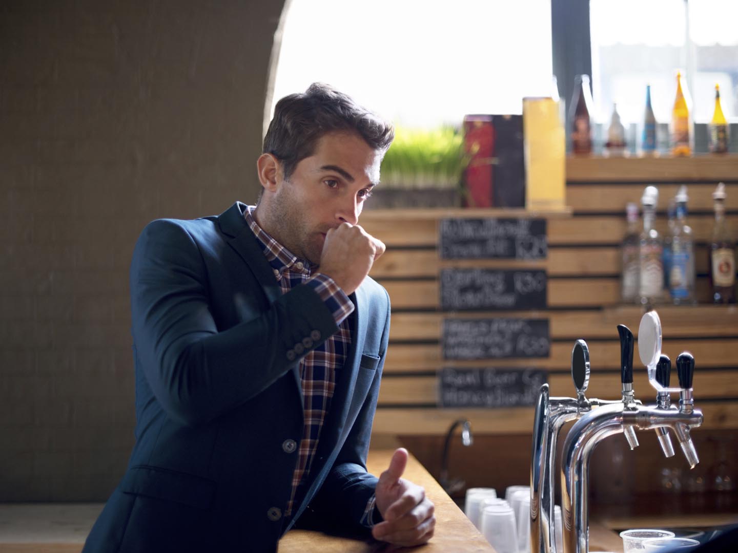 Shot of a handsome young man at the bar covering his mouth