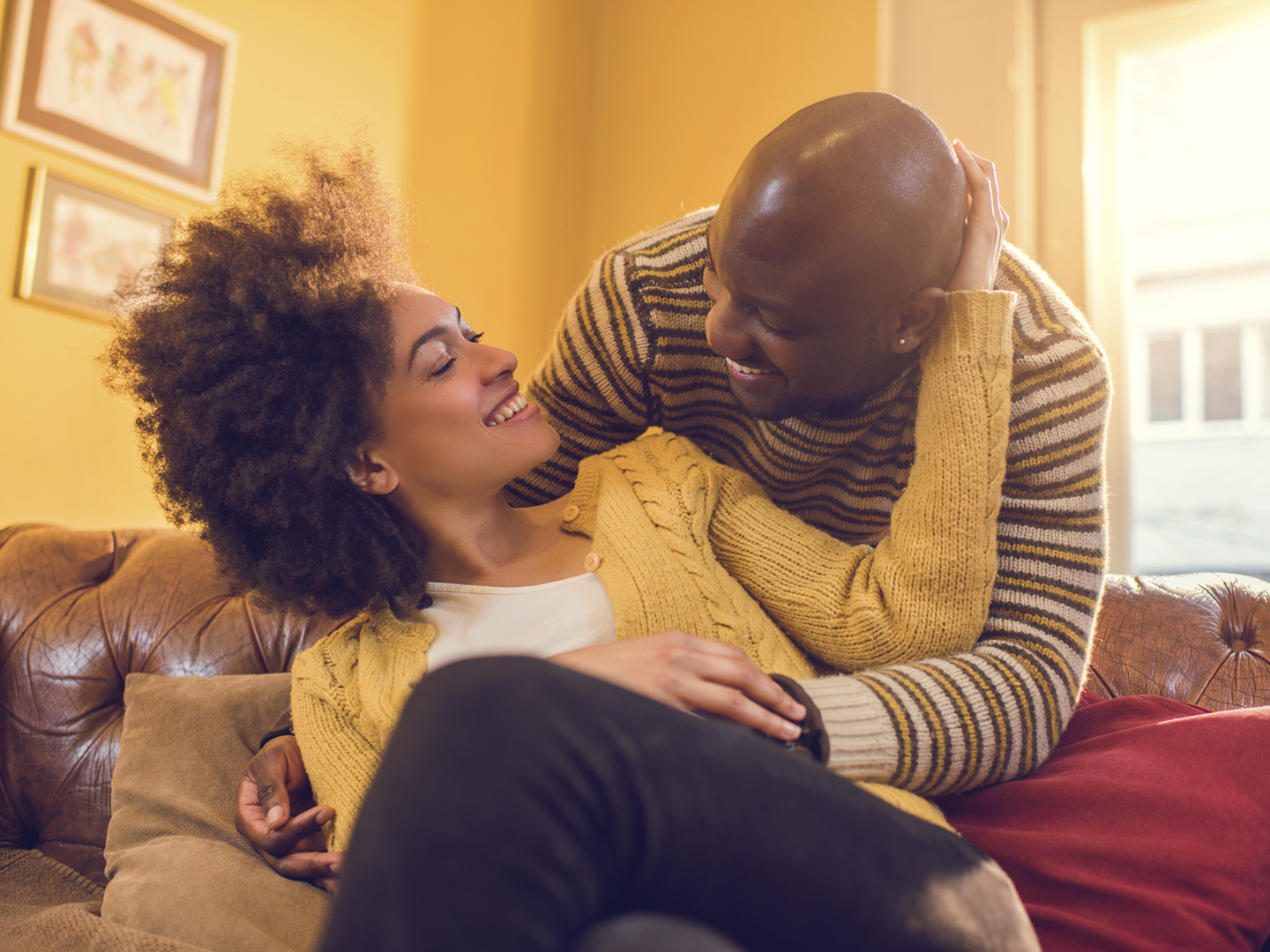 Happy African American couple talking to each other at home. They are full of love toward each other.