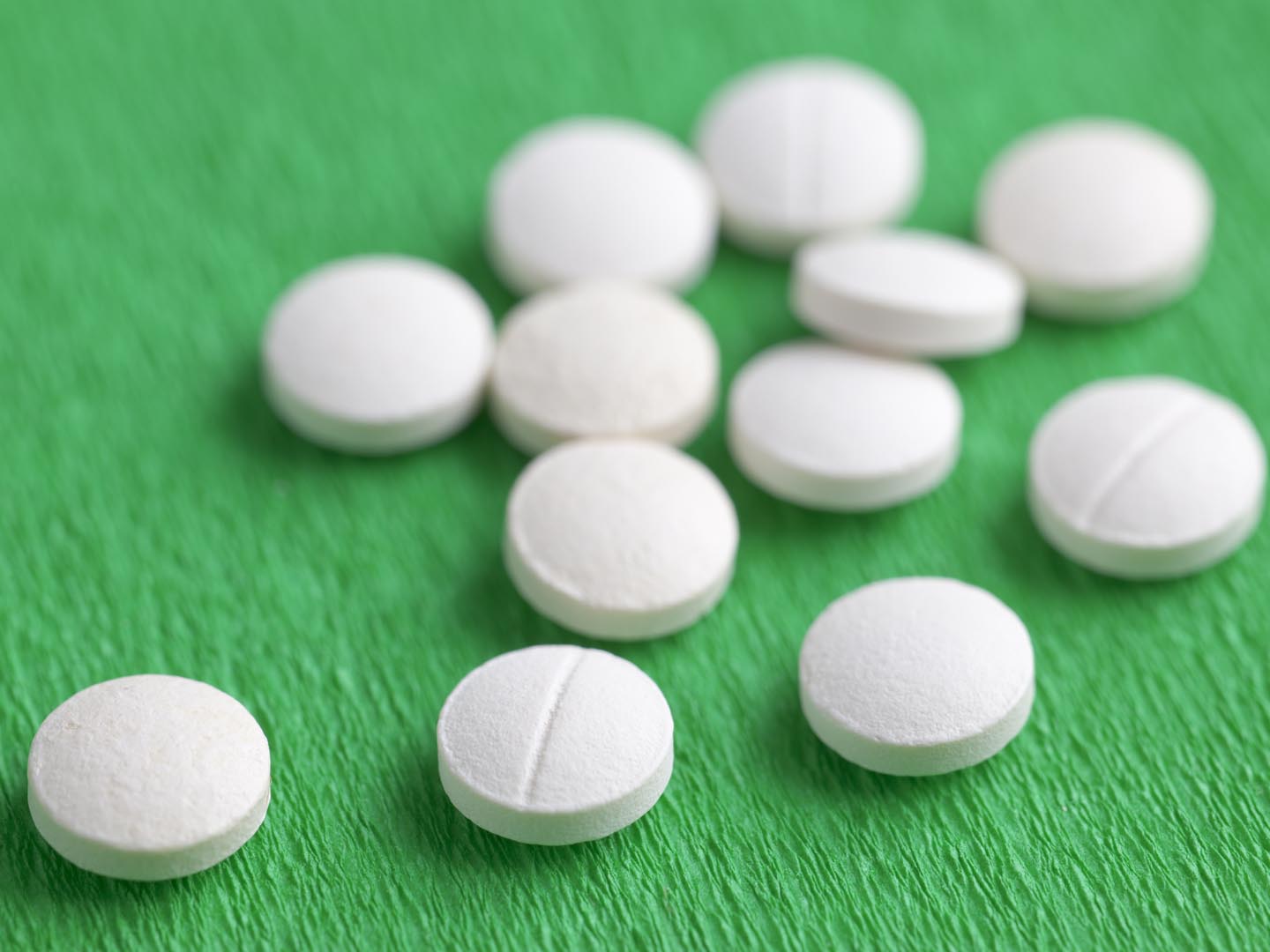Close-Up of White Melatonin Natural Medicine Sleeping Pills on Green Background