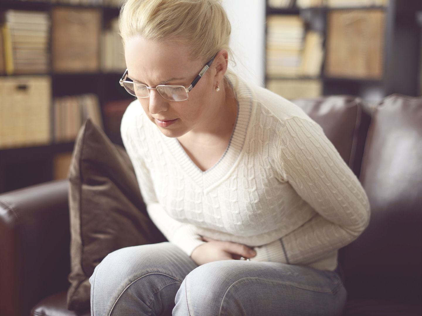 woman sitting on a sofa and holding her stomach,abdominal pain