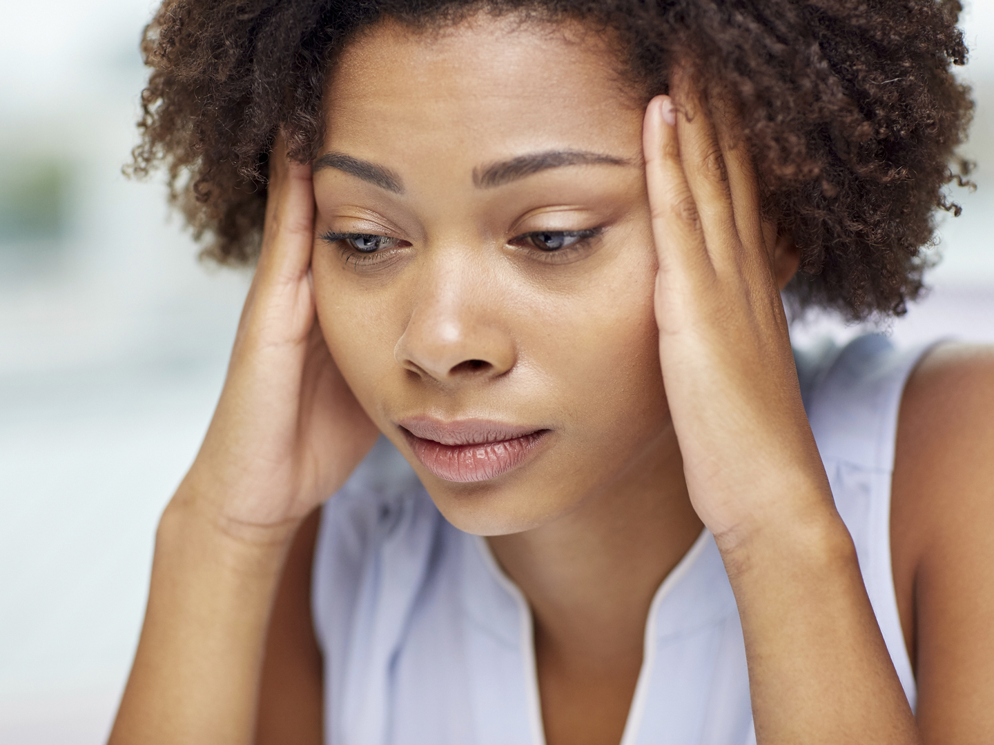 people, emotions, stress and health care concept - unhappy african american young woman touching her head and suffering from headache