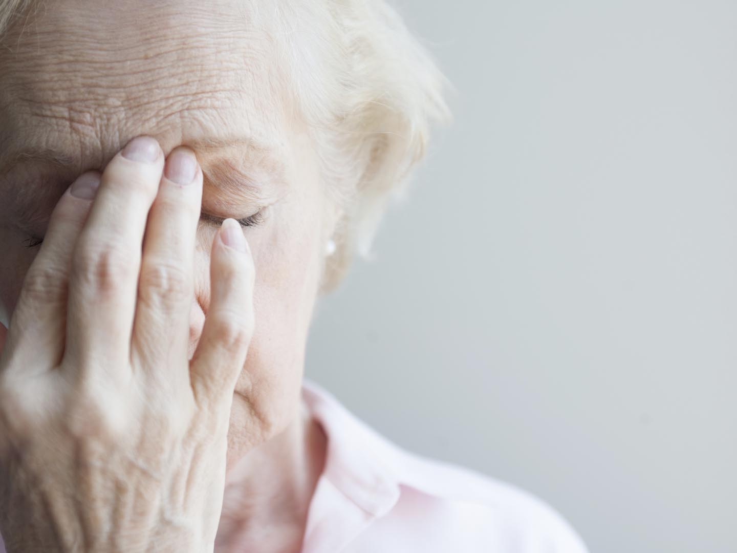 Senior woman with her hand on her forehead with sinus pain