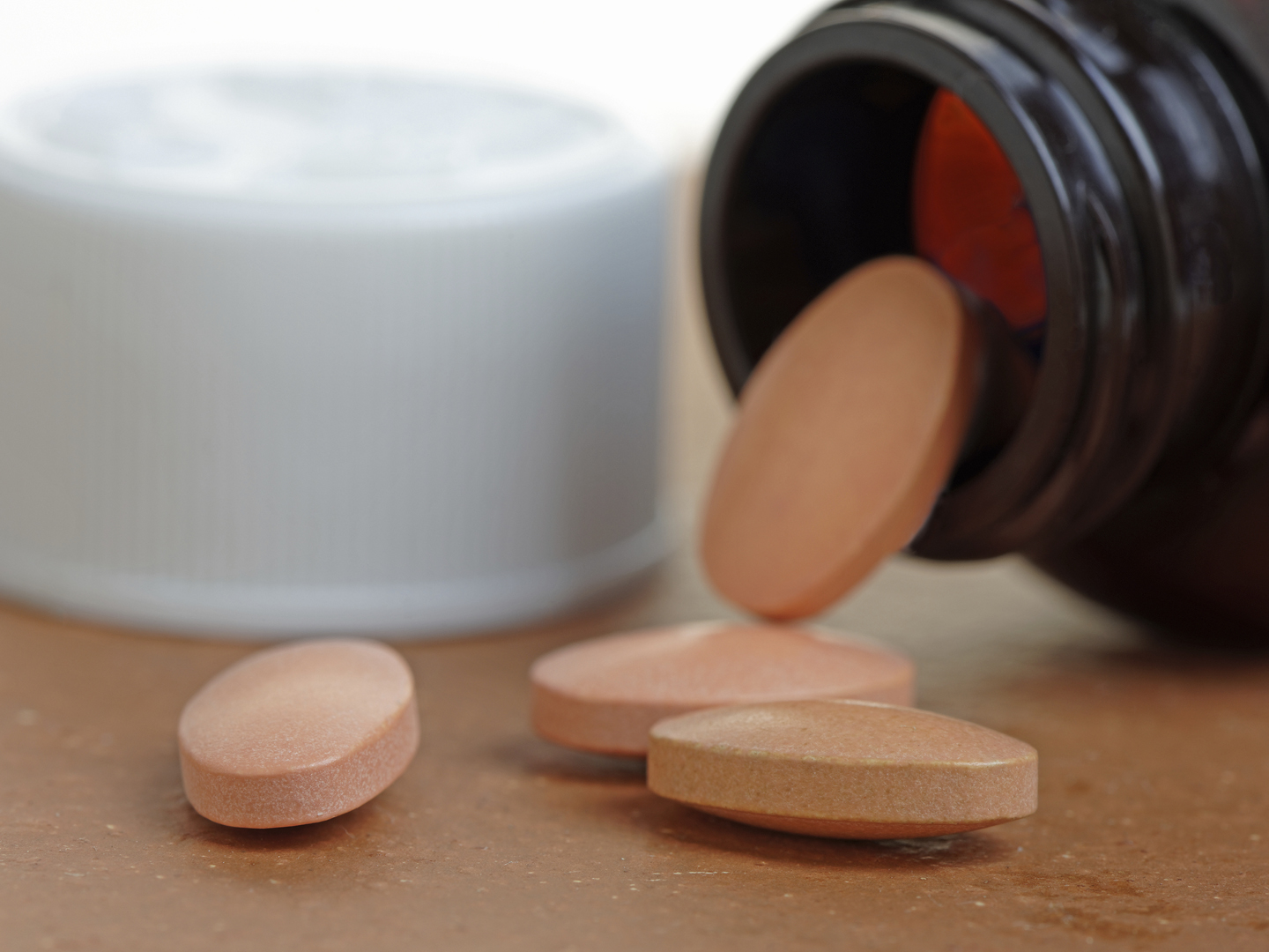Statins, or generic pills, pouring from a bottle. Close up with shallow depth of field