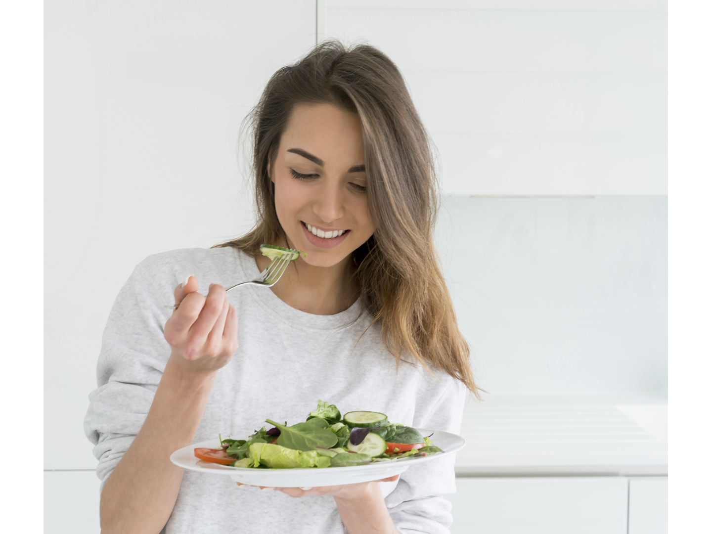 Healthy young woman dieting and eating a salad at home