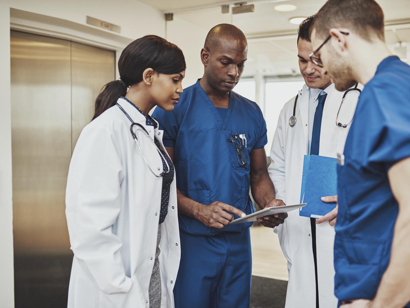 Black surgeon giving instruction to medical team mixed races using tablet