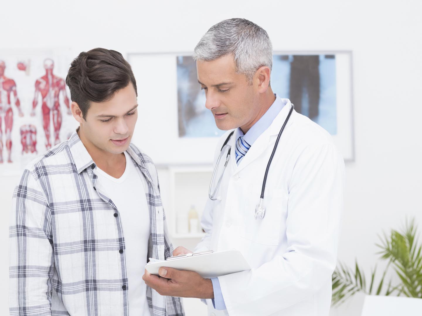 Doctor showing clipboard to his patient in medical office