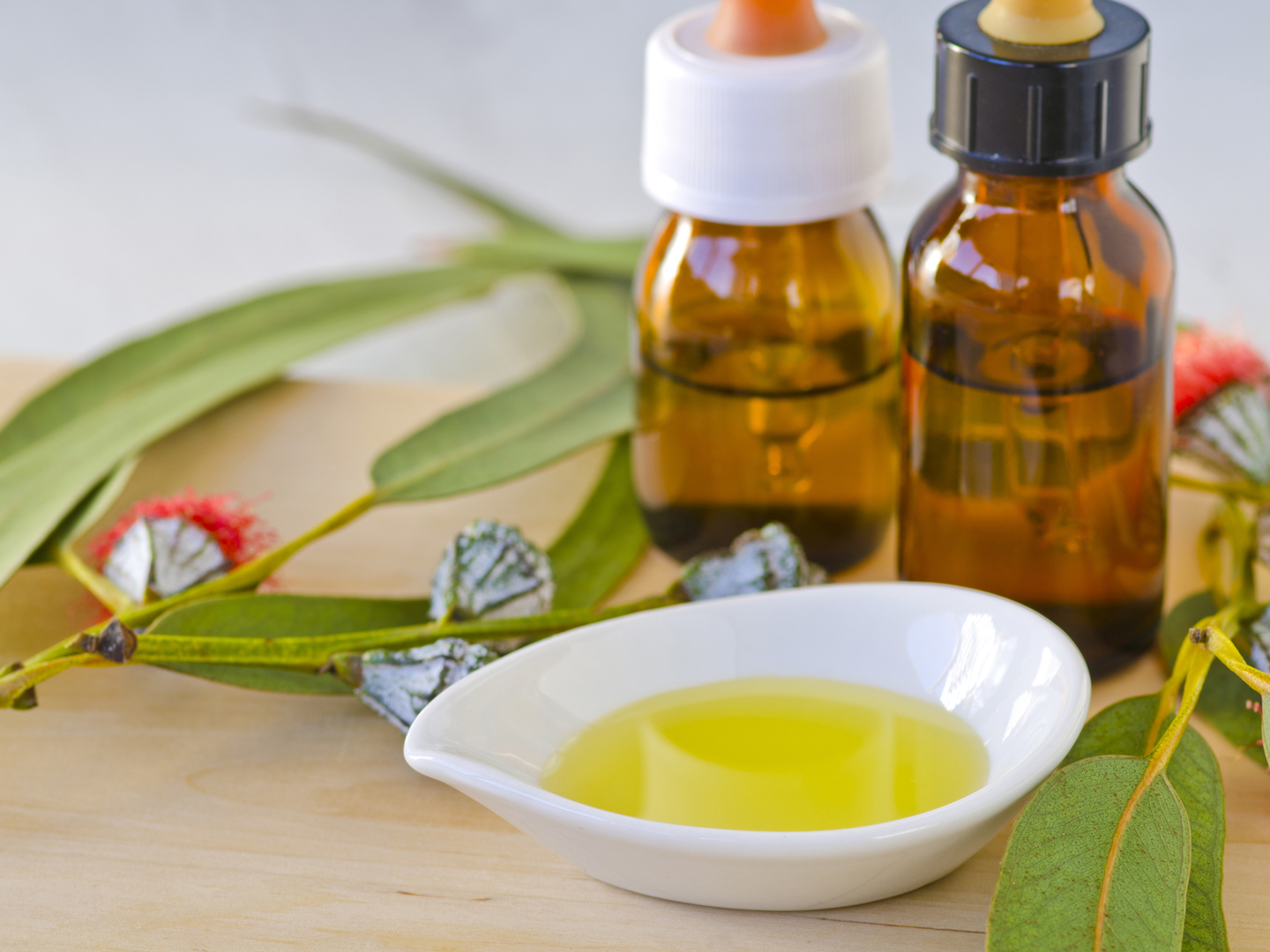 Eucalyptus leaves and essential oil on wooden cutting board. Selective focus. Taken in daylight.