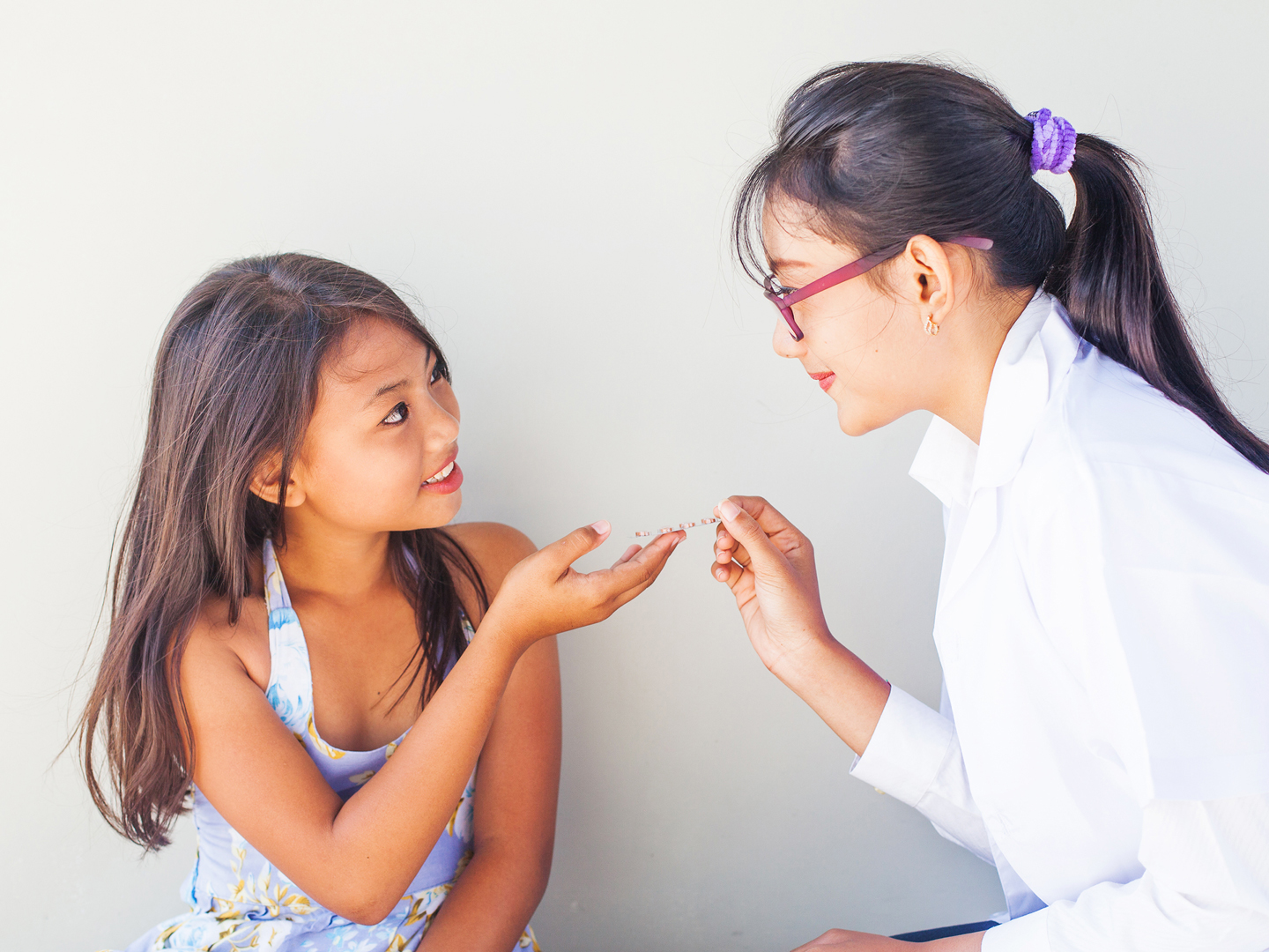 Asian young doctor giving medicine to little asian girl