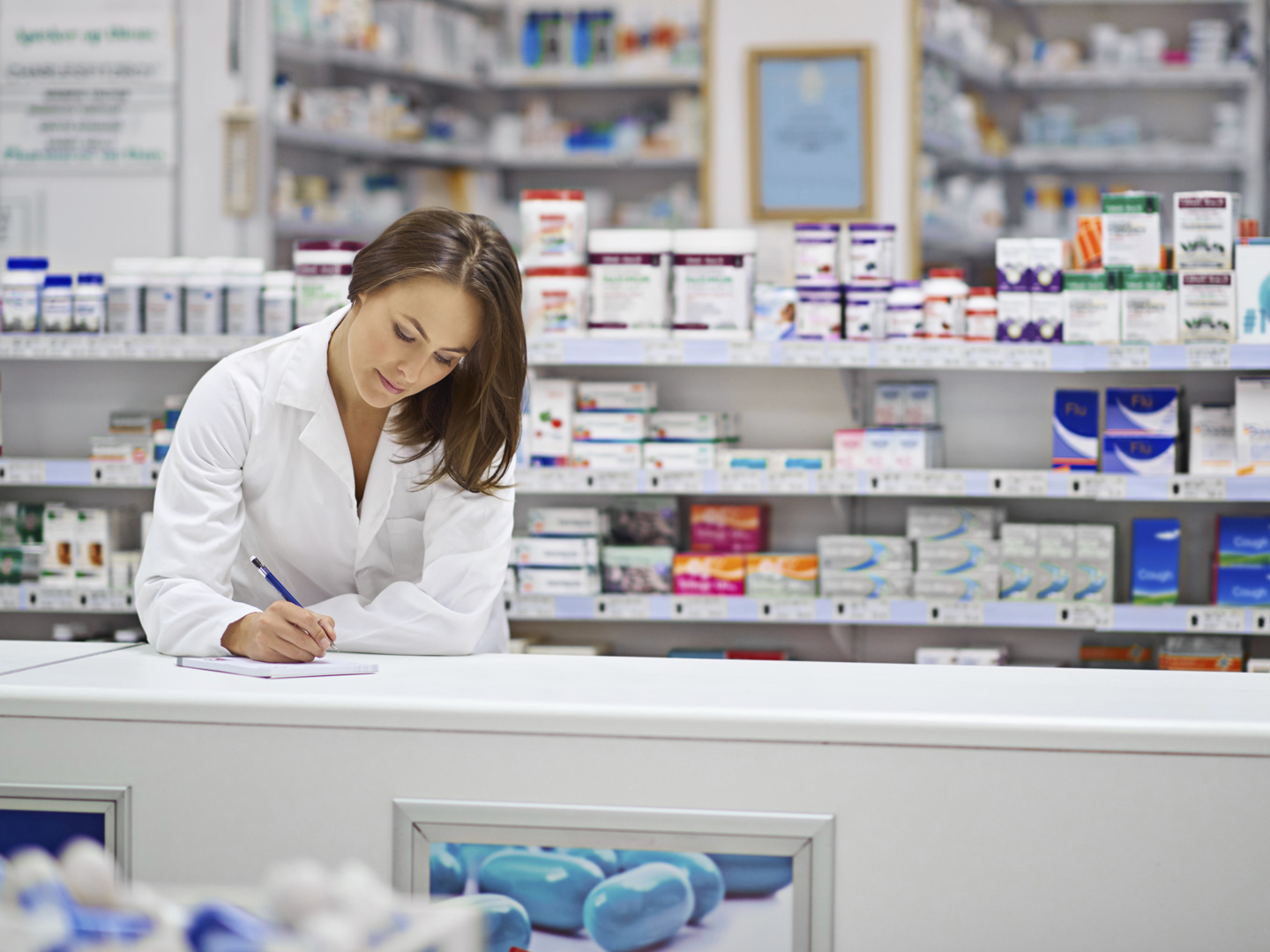 Shot of an attractive young pharmacist working at the prescription counter. The commercial product(s) or designs displayed in this image represent simulations of a real product, and are changed or altered enough so that they are free of any copyright infringements. Our team of retouching and design specialists custom designed these elements for each photo shoot http://195.154.178.81/DATA/i_collage/pi/shoots/785200.jpg