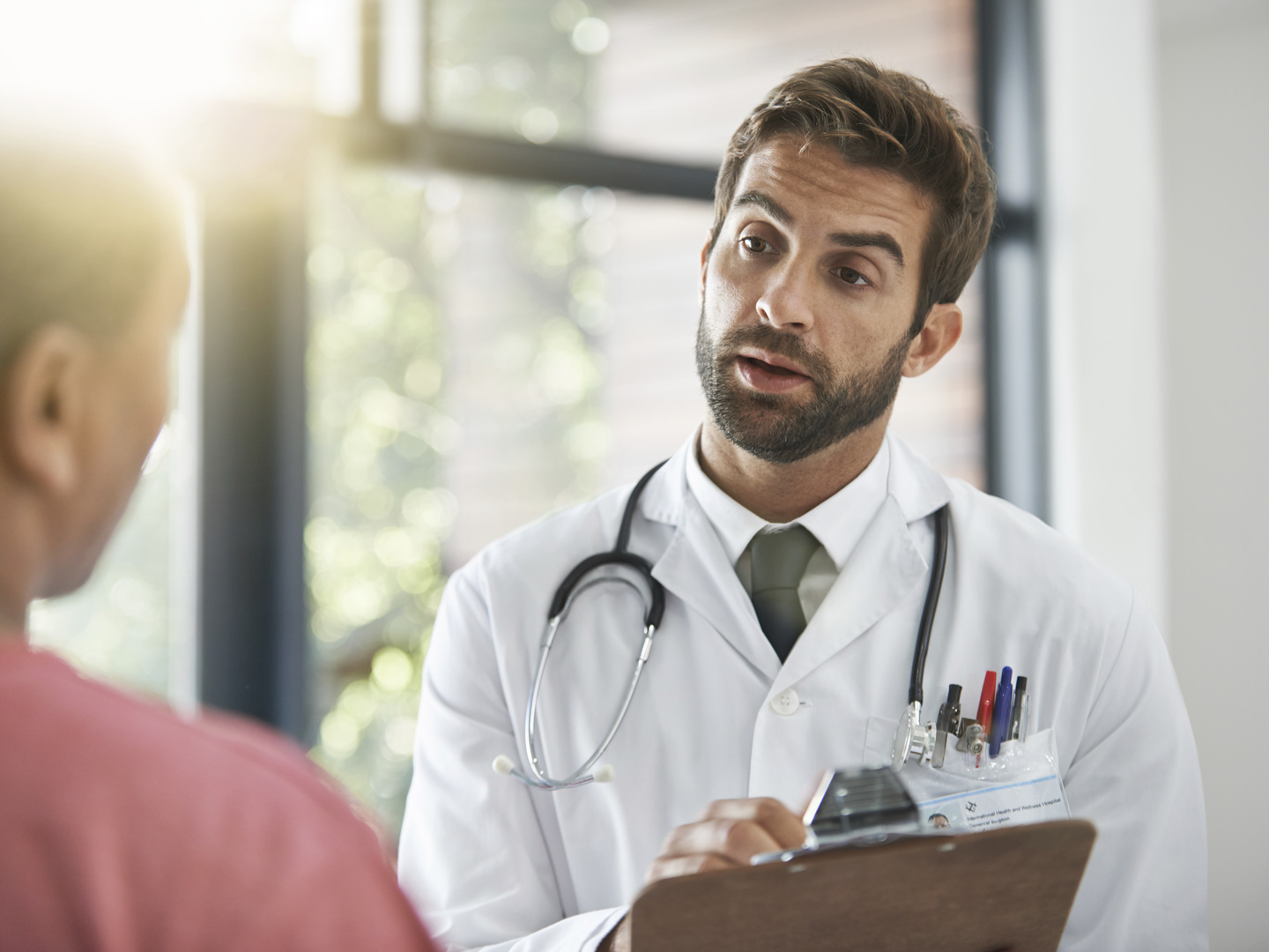 Shot of a male doctor talking with a patient in a hospital lobby