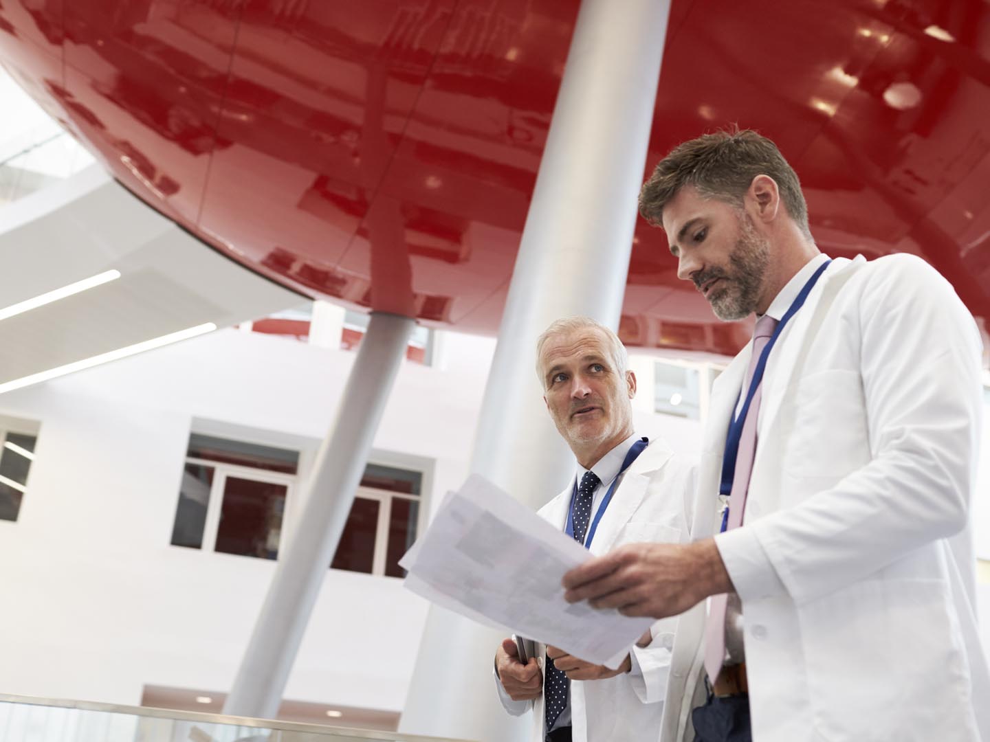 Two Doctors Talking As They Walk Through Modern Hospital