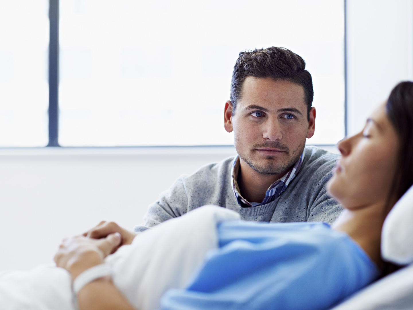 Shot of a woman lying in a hospital bed being comforted by her husband