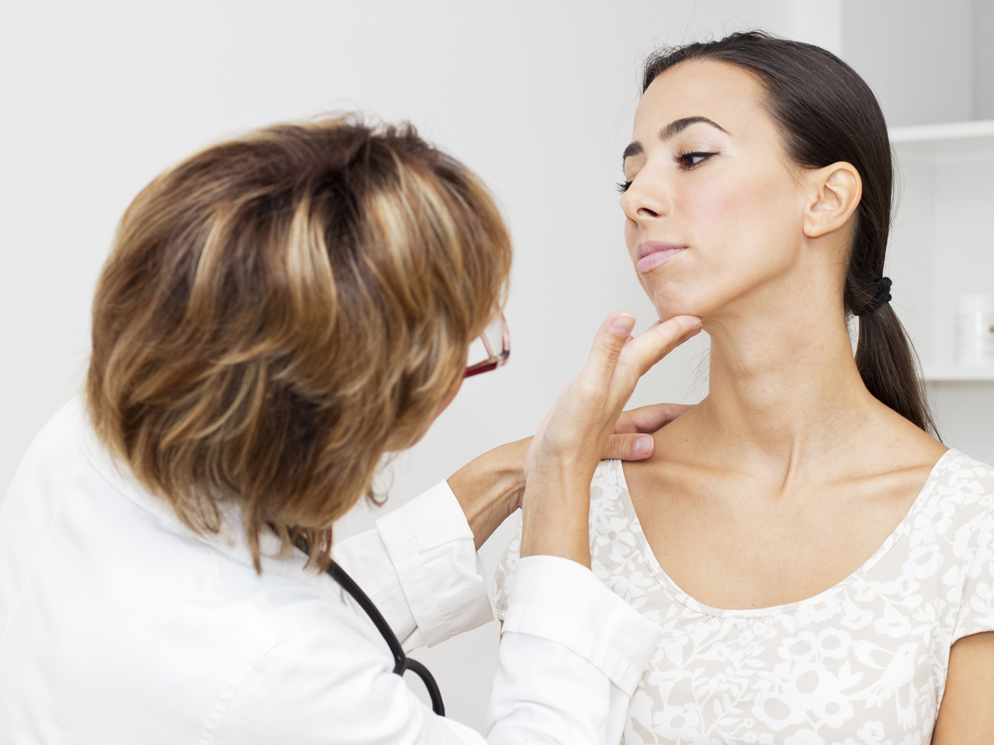 Mature female doctor examining her young female  patient.