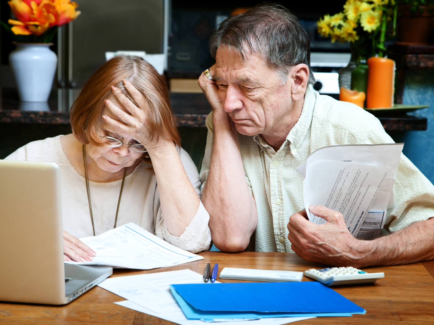 Senior couple at home reacting to many bills