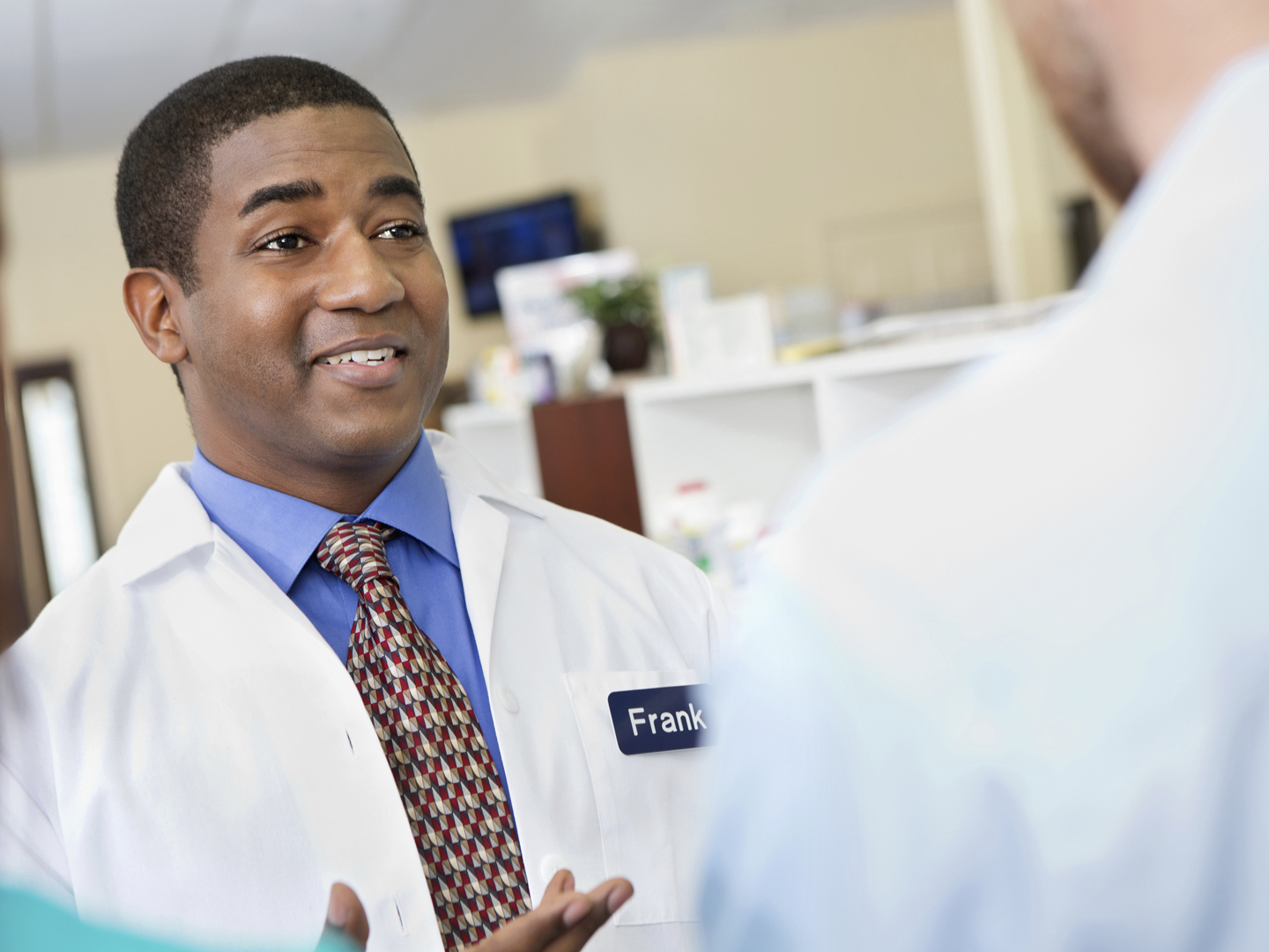 Neighborhood pharmacist answering customer questions in pharmacy