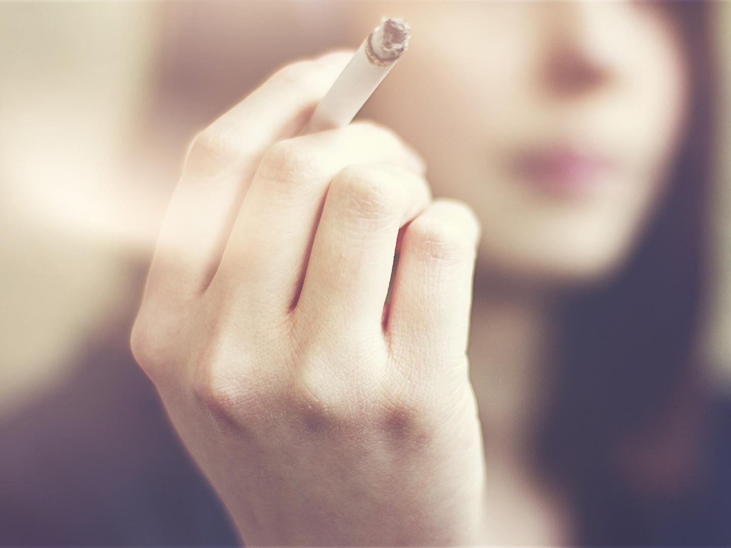 Woman hands holding cigarette outdoor.