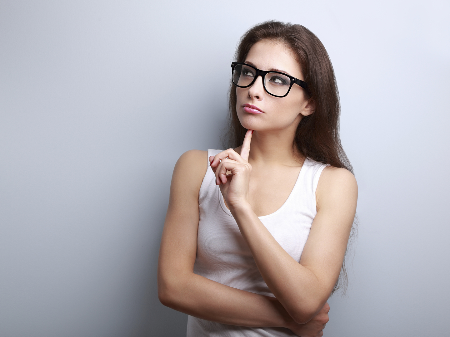 Beautiful serious thinking young woman looking up on empty copy space