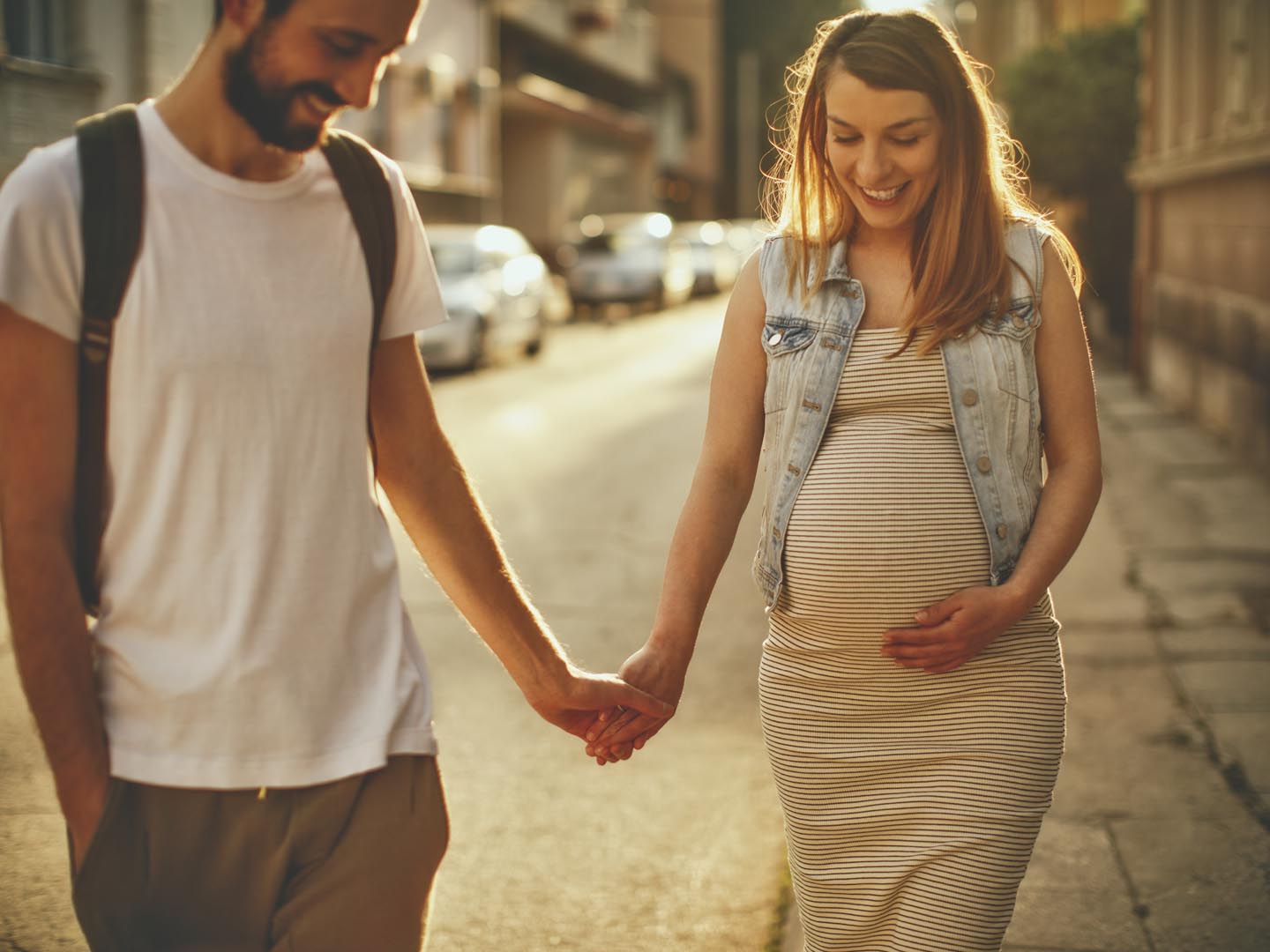 Photo of a young couple, soon to become parents, enjoy their walk on a beautiful sunny day