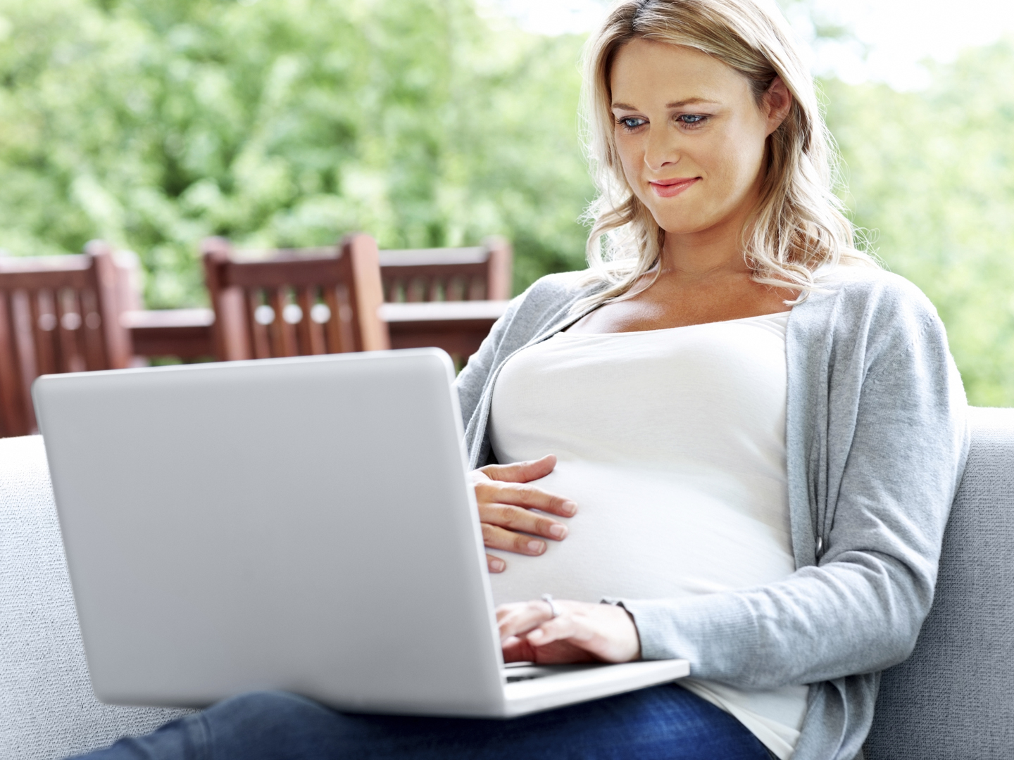 Portrait of pregnant woman working on laptop while relaxing on couch