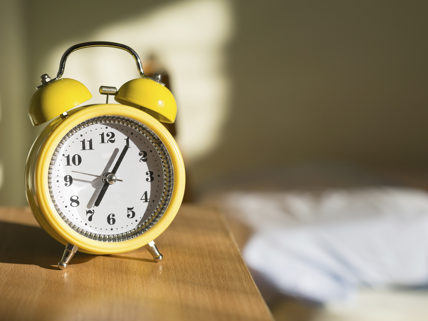 Yellow alarm clock on a night table, close up.