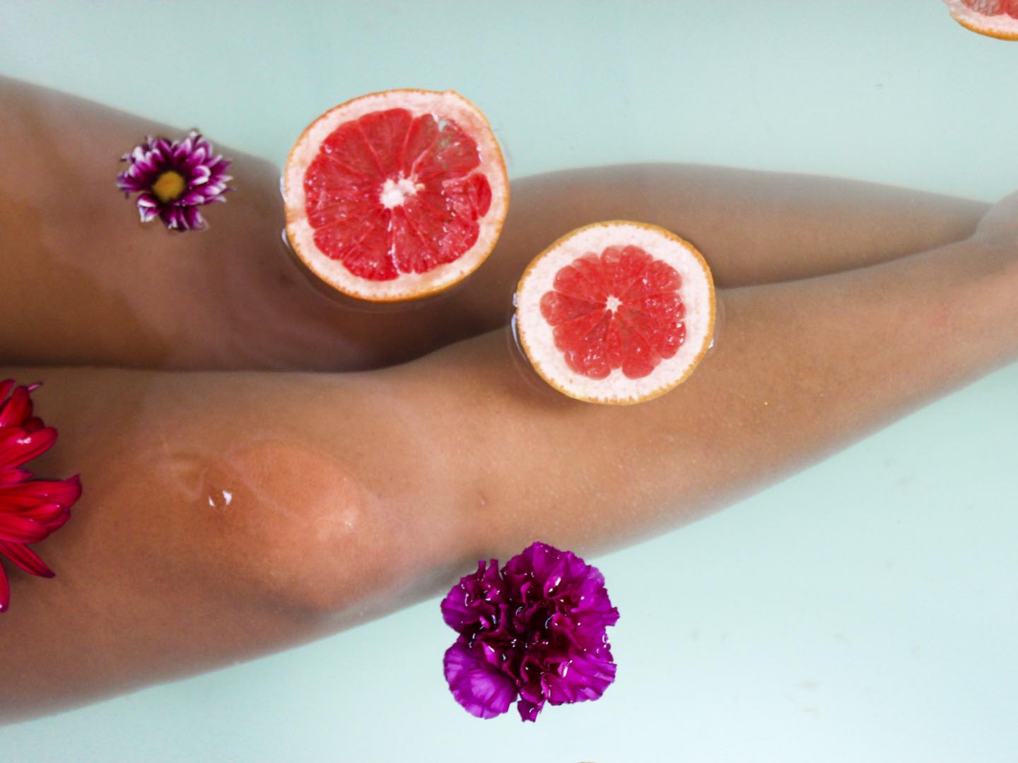 Woman soaking her legs in a relaxing tub with citrus and botanicals at the spa.