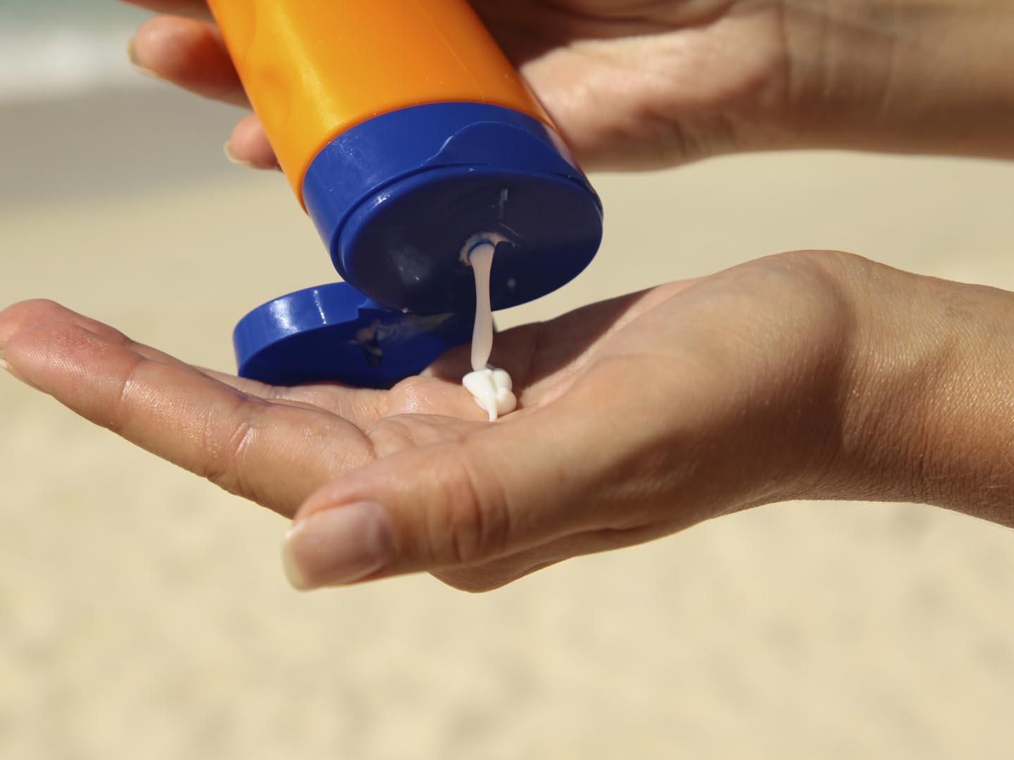 woman holding and applying suntan lotion on a beach